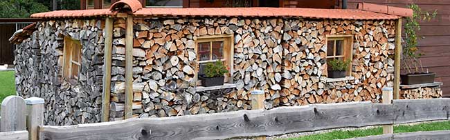 Holzstapel mit Fenster - windgeschützter Sitzplatz mit wieteren Holzstapeln vor dem Haus - Bild klicken!