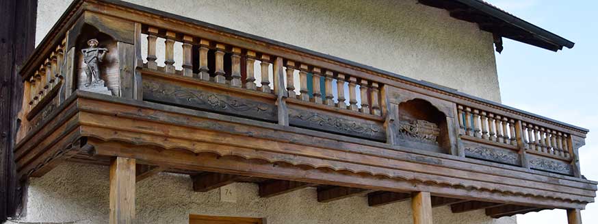 Balkon mit reich geschnitzten Figuren an einem Bauernhof in Ussenburg