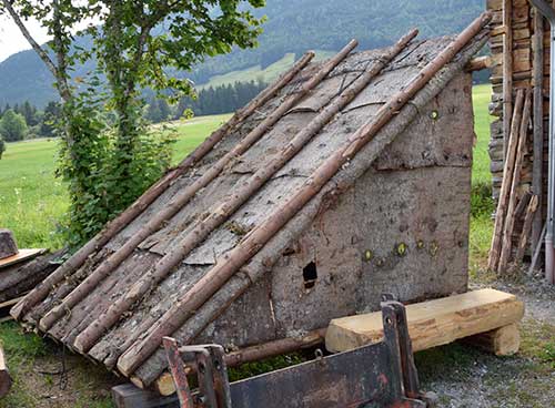 Holzstaplergemeinde Trauchgau -  Holzer Hütteaus Fichtenrinde im Wald